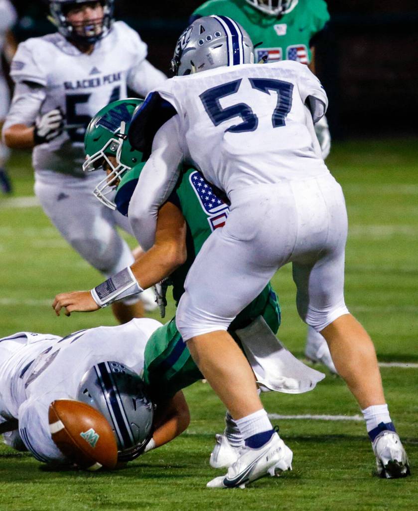 Glacier Peaks Konner Meyer, 57, forces a fumble by Woodinvilles Theo Grothen with Glacier Peaks Jacob Erickson, left, assisting Thursday evening at Pop Keeney Stadium in Bothell on September 16, 2021. (Kevin Clark / The Herald)