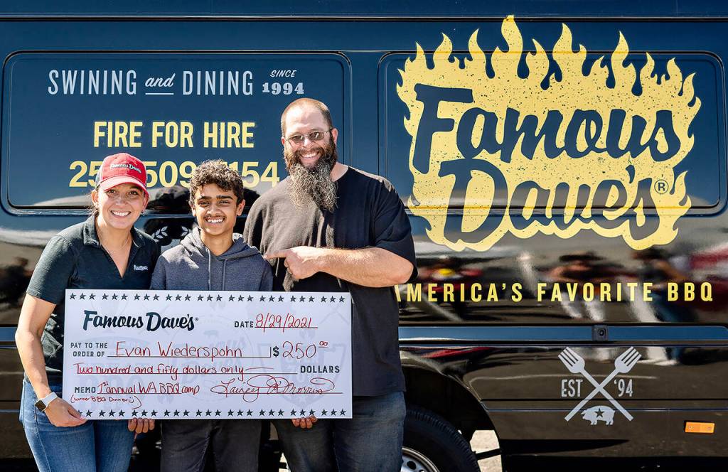 Evan Wiederspohn, 15, (center) holds the winning check for his appetizer from Elaina Morris (left) president and CEO of Ascend Hospitality Group. He started competing in cookoffs with his father, Brandon (right), when he was 10. (Ascend Hospitality Group)