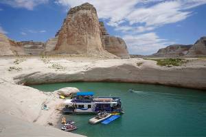 A houseboat rests in a cove at Lake Powell Friday, July 30, 2021, near Page, Ariz. This summer, the water levels hit a historic low amid a climate change-fueled megadrought engulfing the U.S. West. (AP Photo/Rick Bowmer)