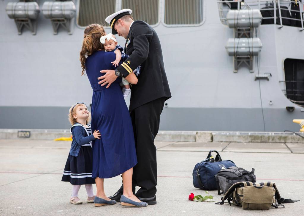 Lt. David Larkin hugs his wife and children after his return from deployment aboard the USS Kidd on Friday in Everett. This was his first time seeing his new baby daughter, Lucy. (Olivia Vanni / The Herald)