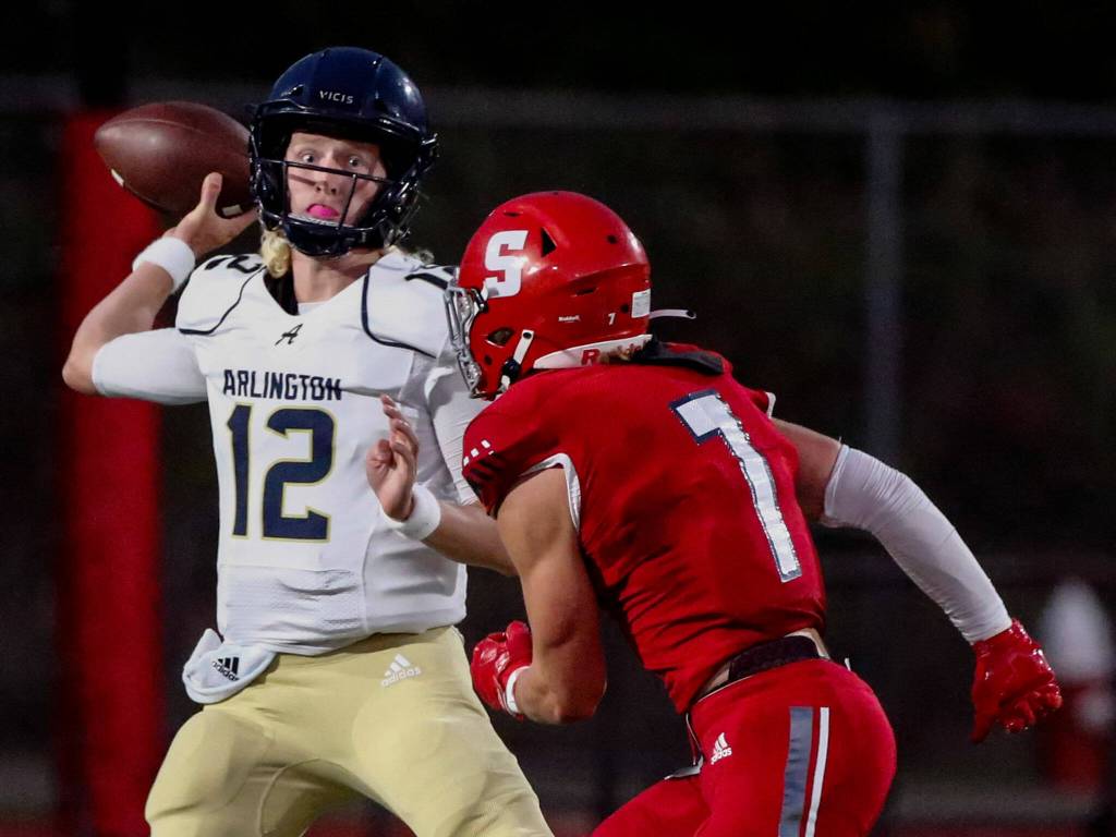 Arlingtons Trent Nobach passes in the face of Stanwoods defensive pressure during the Stilly Cup on Friday night at Stanwood High School. (Kevin Clark / The Herald)