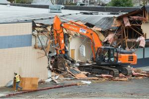 Crews demolish the strip mall at 10th and Broadway, near the Washington State University Everett campus, on Monday, Sept. 27, 2021 in Everett, Washington. Crews started tearing down a strip mall Monday on property that will soon expand Everett Community College’s footprint across Broadway. The Cascade Learning Resource Center project will total 65,000 square feet. It will expand the college’s tutoring resources as well as house the library, writing center and other academic support programs. (Andy Bronson / The Herald)