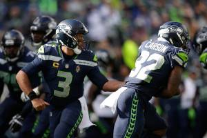 Seattle Seahawks quarterback Russell Wilson (3) hands off to running back Chris Carson (32) during an NFL football game against the Tennessee Titans, Sunday, Sept. 19, 2021, in Seattle. (AP Photo/John Froschauer)