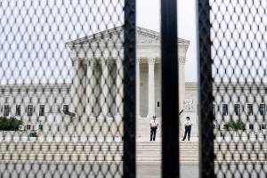 FILE - In this Sept. 17, 2021 file photo U.S. Capitol police officers walk near fencing around the Supreme Court in Washington. Twenty-five media and transparency groups are asking the Washington Supreme Court to allow the release of the names of the Seattle police officers who attended events in Washington D.C. on Jan. 6 — the day of the insurrection. The Reporters Committee for the Freedom of the Press and the news organizations are asking the court to deny an injunction filed by the officers that seeks to block the release of public records that identify the officers. (AP Photo/Brynn Anderson, file)