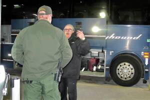 In this Thursday, Feb. 13, 2020 photo, a worker, right, speaks with a Customs and Border Protection agent seeking to board a Greyhound bus headed for Portland, Ore., at the Spokane Intermodal Center, a terminal for buses and Amtrak in Spokane, Wash. A Customs and Border Protection memo obtained by The Associated Press confirms that bus companies such as Greyhound do not have to allow Border Patrol agents on board to conduct routine checks for illegal immigrants, contrary to Greyhound's long insistence that it has no choice but to let the agents on board. (AP Photo/Nicholas K. Geranios)