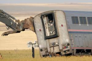 A piece of heavy equipment props up a leaning train car, Sunday, Sept. 26, 2021, that was part of an Amtrak train that derailed Saturday, near Joplin, Mont. The westbound Empire Builder was en route to Seattle from Chicago with two locomotives and 10 cars. (AP Photo/Ted S. Warren)