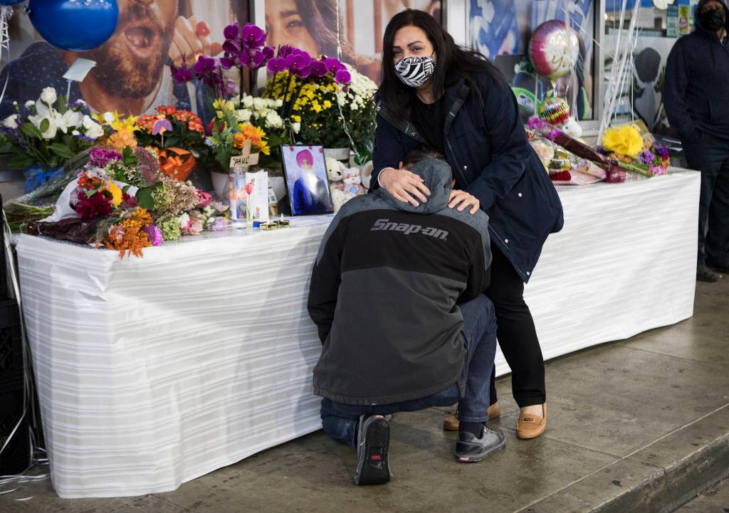 Kelly Johal consoles a man as he cries in front of a memorial for TejPal Singh on Wednesday in Lynnwood. (Olivia Vanni / The Herald)