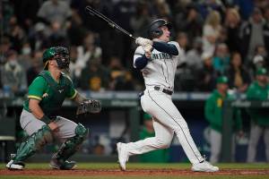Seattle Mariners' Jarred Kelenic follows through on a two-RBI double as Oakland Athletics catcher Yan Gomes, left, looks on, during the sixth inning of a baseball game, Wednesday, Sept. 29, 2021, in Seattle. Mitch Haniger and Ty France scored on the play. (AP Photo/Ted S. Warren)