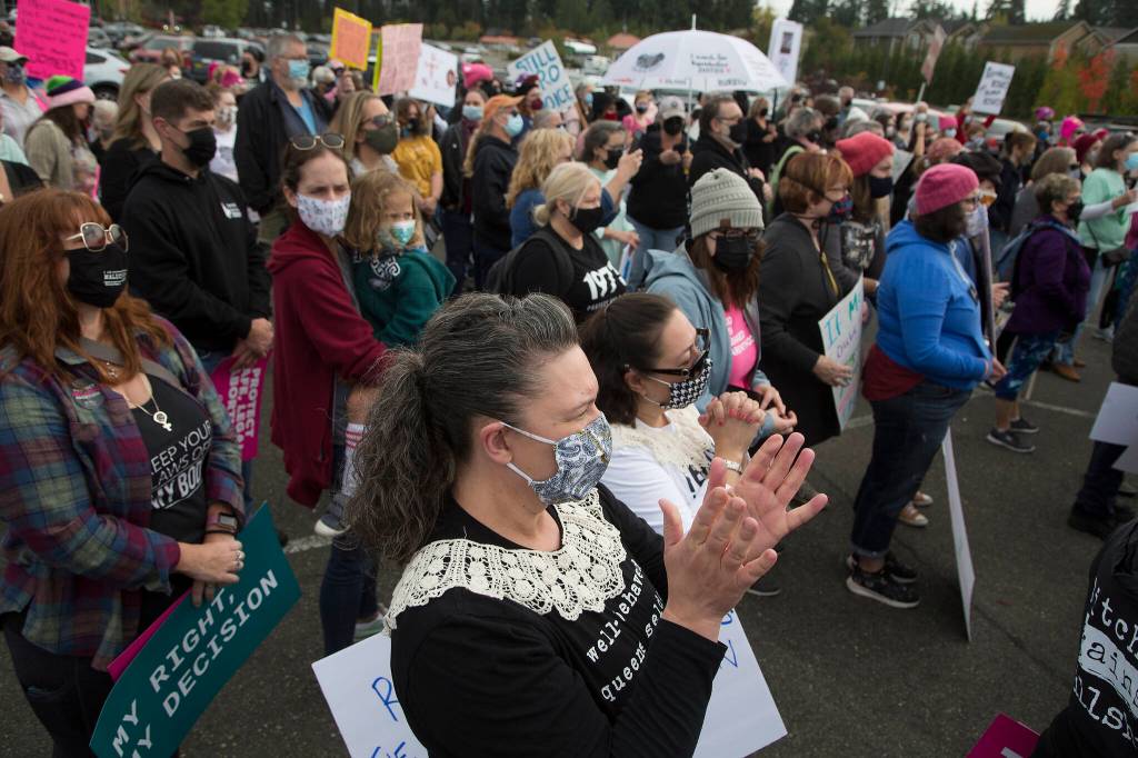 Paulette Lee, wearing a Ruth Bader Ginsburg lace, claps as she and several hundred activists cheer Saturday before marching in support of reproductive rights in Everett. The demonstration started at Everett Mall and continued along Highway 99. (Andy Bronson / The Herald)