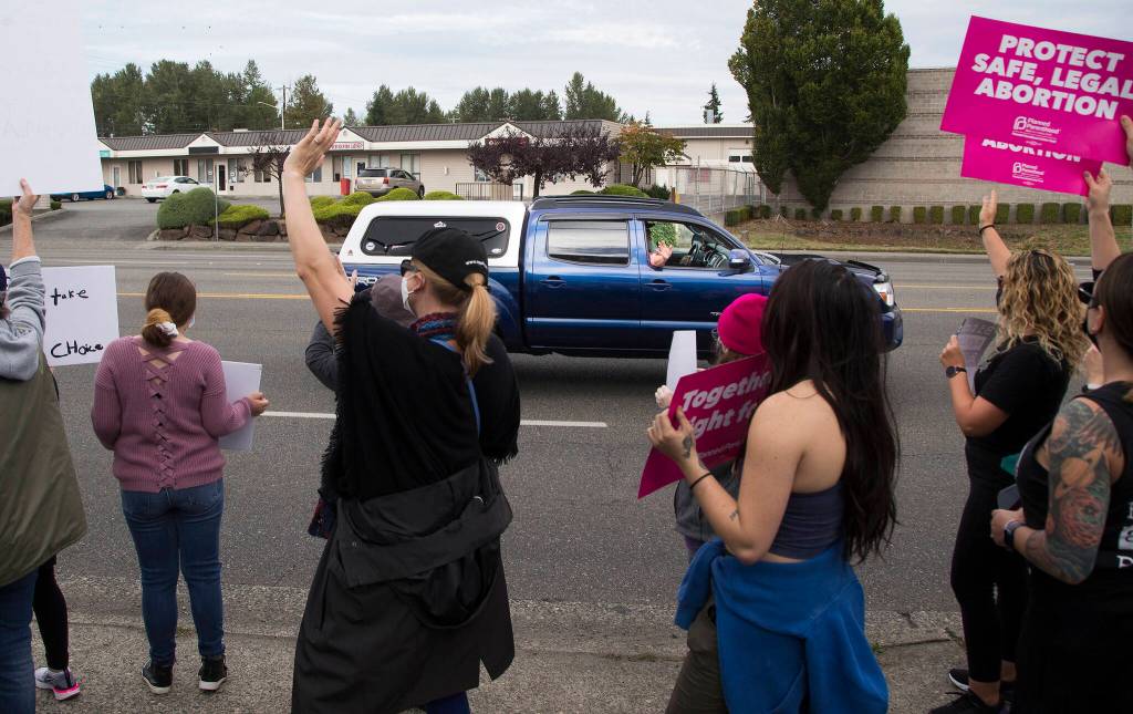 A passenger in a truck waves at several hundred activists who march in support of reproductive rights along Highway 99 on Saturday, Oct. 2, 2021 in Everett, Washington. (Andy Bronson / The Herald)