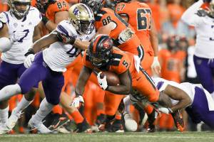 Oregon State running back Deshaun Fenwick (5) is brought down by Washington's Edefuan Ulofoshio, left, and Cameron Williams during the first half of an NCAA college football game Saturday, Oct. 2, 2021, in Corvallis, Ore. (AP Photo/Amanda Loman)