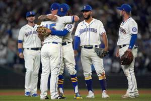 Seattle Mariners third baseman Kyle Seager (15) hugs teammates as he is subbed out of a baseball game against the Los Angeles Angels during the ninth inning, Sunday, Oct. 3, 2021, in Seattle. (AP Photo/Ted S. Warren)