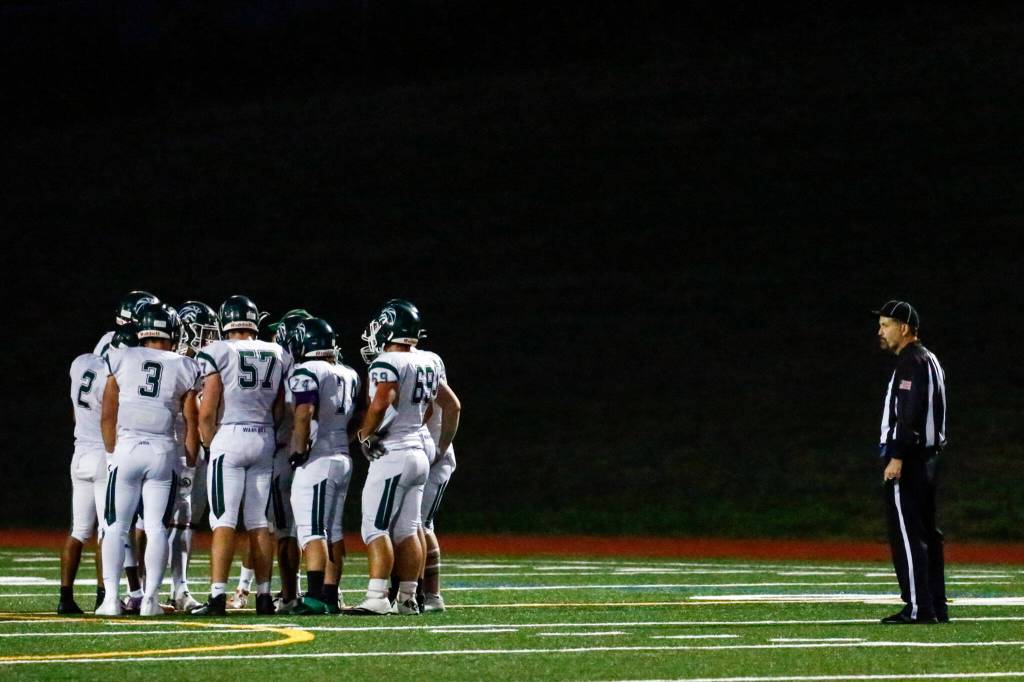 Mark Guffey tracks the Edmonds-Woodway huddle during a time out against Monroe Friday night at Monroe High School on October 1, 2021. (Kevin Clark / The Herald)