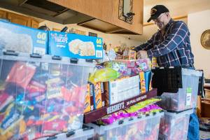 Stephen Fay smiles as he begins dumping candy into a large storage container at his home on Friday, Oct. 29, 2021 in Marysville, Wa. (Olivia Vanni / The Herald)