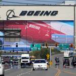 Traffic drives in view of a massive Boeing Co. production plant, where images of jets decorate the hangar doors, Friday, April 23, 2021, in Everett, Wash. (AP Photo/Elaine Thompson)