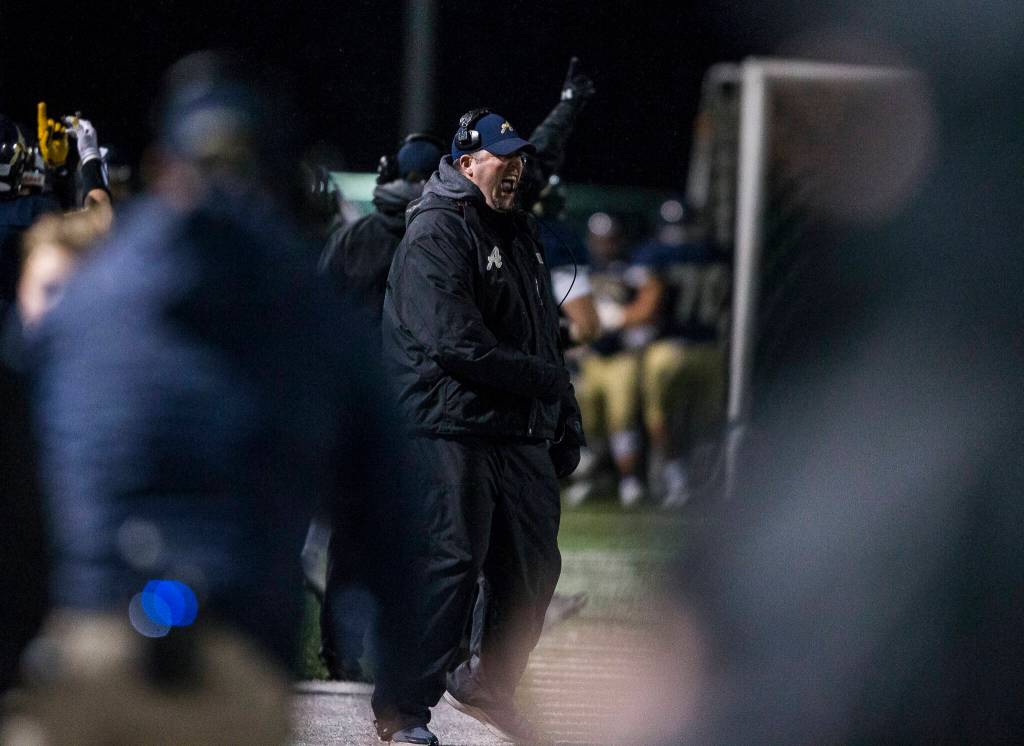 Arlington coaches celebrate another touchdown Friday during the game against Marysville-Pilchuck in Arlington. (Olivia Vanni / The Herald)