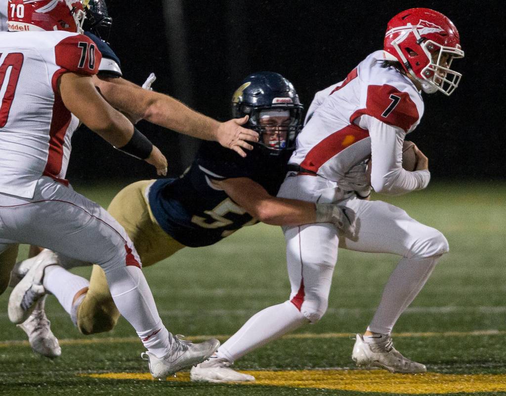 Arlington defensive lineman Josh Snow sacks Marysville Pilchuck quarterback Jace Luton. (Olivia Vanni / The Herald)