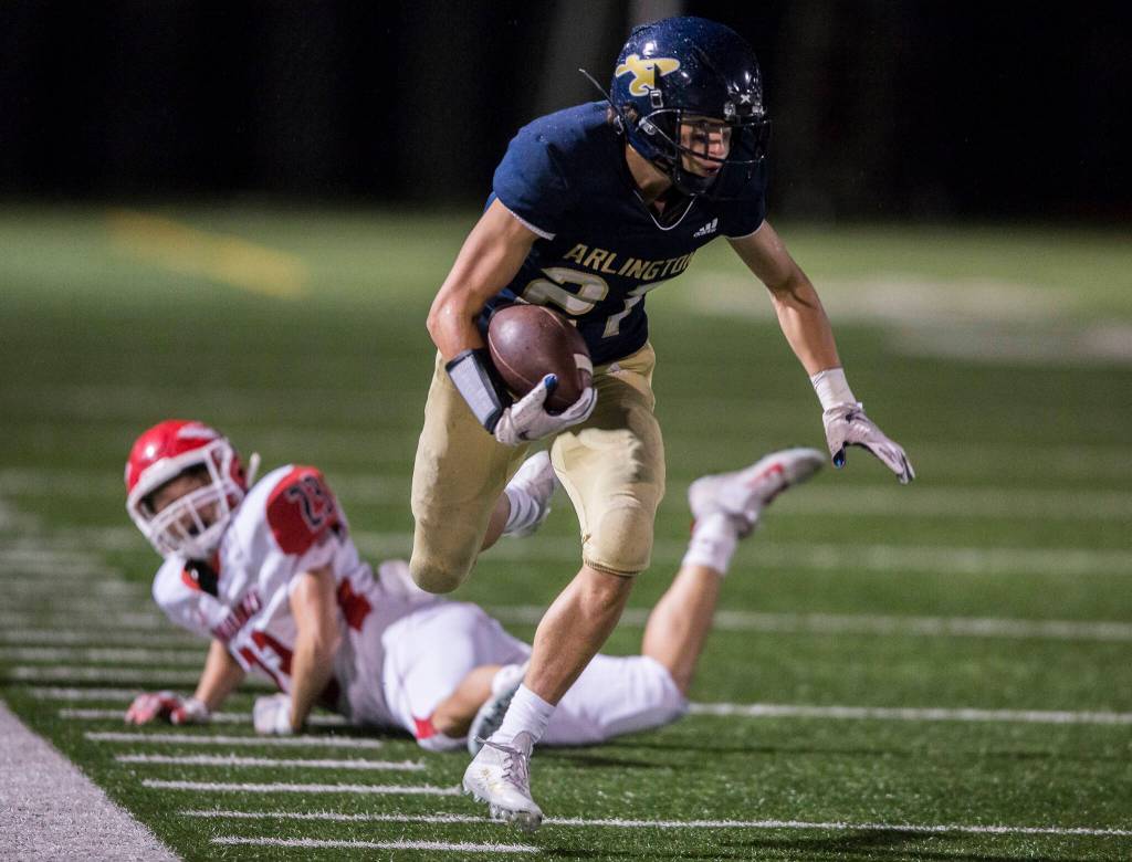 Arlingtons Holden Erken escapes a tackle and runs down the sideline Friday during the game against Marysville-Pilchuck in Arlington. (Olivia Vanni / The Herald)