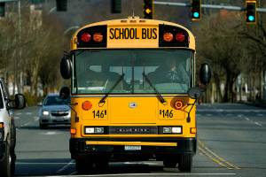 An Issaquah School District school bus waits at an intersection near where a rally to encourage wider opening of in-person learning was being held, Wednesday, Feb. 24, 2021, in Issaquah, Wash., east of Seattle. Students in kindergarten and lower-elementary grades recently returned to school in the district under a hybrid in-person learning program, but older elementary, middle-, and high school students are still being taught remotely. (AP Photo/Ted S. Warren)