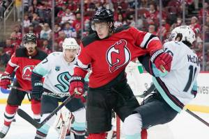 New Jersey Devils' Ryan Graves (33) knocks down Seattle Kraken's Jared McCann (16) during the second period of an NHL hockey game Tuesday, Oct. 19, 2021, in Newark, N.J. (AP Photo/Frank Franklin II)