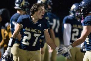 Arlington's Holden Erken yells and high-fives a teammate after beating Marysville-Pilchuck on Friday, Oct. 15, 2021 in Arlington, Wa. (Olivia Vanni / The Herald)