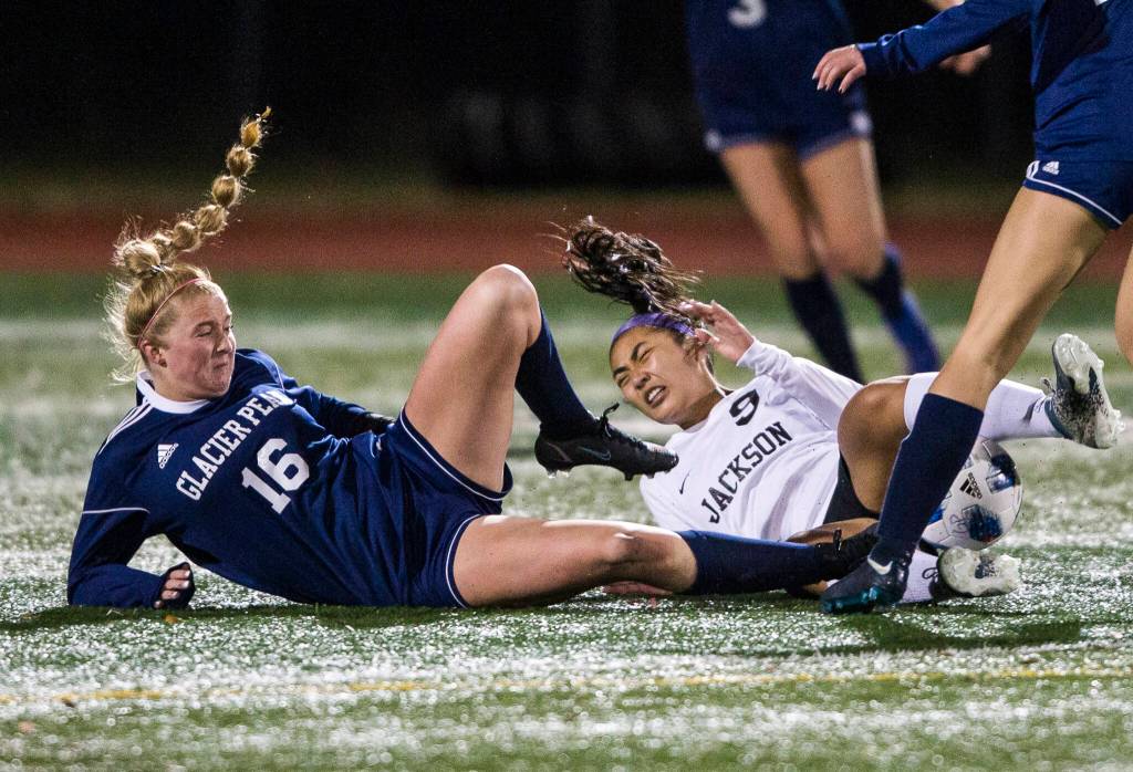 Glacier Peaks Kate Sprink and Jacksons Emilyn Pham both slide in for a tackle during the game Tuesday in Snohomish. (Olivia Vanni / The Herald)