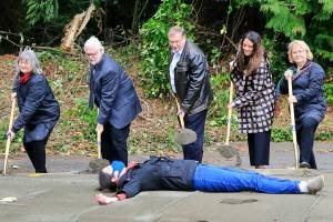 City officials break ground for the Community Justice Center Wednesday afternoon with Elizabeth Lunsford laying in protest in Lynnwood on October 27, 2021. (Kevin Clark / The Herald)