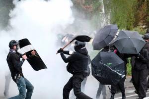 FILE - An anti-fascist protester swings a baton as members of the far-right Proud Boys advance during clashes between the politically opposed groups on Sunday, Aug. 22, 2021, in Portland, Ore. The city's leaders were told this week that Portland's "badly damaged" reputation – marked by months of destructive protests – continues to hurt the standing of Oregon's largest city in the eyes of potential visitors. (AP Photo/Alex Milan Tracy, File)