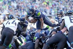 Seattle Seahawks quarterback Geno Smith leaps up and over the line of scrimmage to score a touchdown against the Jacksonville Jaguars during the first half of an NFL football game, Sunday, Oct. 31, 2021, in Seattle. (AP Photo/Stephen Brashear)