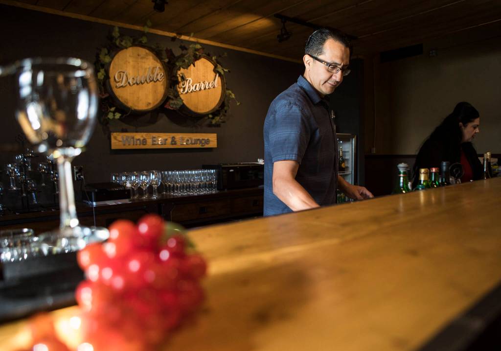 Double Barrel Wine Bar and Lounge owner Lionel Madriz and his wife, Ana Madriz, sort items behind the bar. (Olivia Vanni / The Herald)