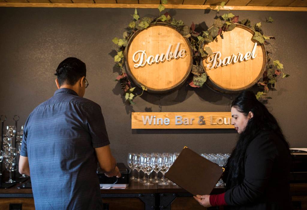 Double Barrel Wine Bar and Lounge owner Lionel Madriz and his wife, Ana Madriz, talk through menu items. (Olivia Vanni / The Herald)