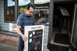 Double Barrel owner Lionel Madriz places a wine sale sign outside of his business on Friday, Nov. 19, 2021 in Snohomish, Wa. (Olivia Vanni / The Herald)