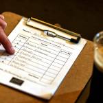 A trivia night player writes down their answers onto a score sheet. (Kevin Clark / The Herald)