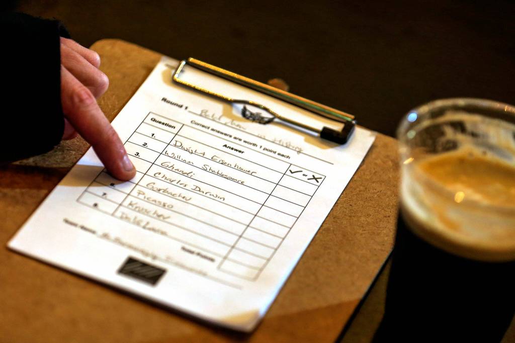 A trivia night player writes down their answers onto a score sheet. (Kevin Clark / The Herald)