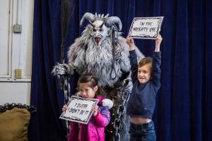 Samantha Breeden, 3, left, and brother John Breeden, 5, right, pose for a photo with Krampus at Oddmall: Emporium of the Weird on Nov. 9, 2019 in Monroe, Wash. (Olivia Vanni / The Herald)