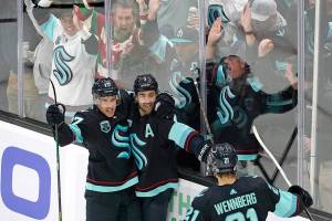 Fans cheer as Seattle Kraken's Jordan Eberle, center, is congratulated by teammates on his third goal of the night against the Buffalo Sabres,, during the third period of an NHL hockey game Thursday, Nov. 4, 2021, in Seattle. (AP Photo/Elaine Thompson)