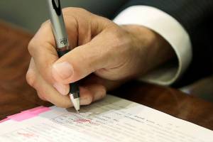 Washington Gov. Jay Inslee uses a red pen to veto sections of the state operating budget, Tuesday, May 21, 2019, at the Capitol in Olympia, Wash. Inslee signed the state's capital, operating, and transportation budgets Tuesday, officially designating funds — and new taxes — to pay for state programs for the next two years. (AP Photo/Ted S. Warren)