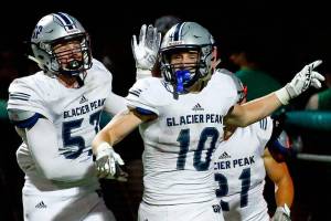 Glacier Peak's Konner Meyer, left, celebrates Glacier Peak's Caden Skibiel's interception and return for a touchdown Thursday evening at Pop Keeney Stadium in Bothell on September 16, 2021. (Kevin Clark / The Herald)