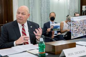 FAA Administrator Steve Dickson speaks to lawmakers as Michael Stumo, holding a photo of his daughter Samya Rose Stumo, and his wife Nadia Milleron, sit behind him during a Senate Committee on Commerce, Science, and Transportation hearing on the implementation of aviation safety reform at the US Capitol in Washington on Wednesday, Nov. 3, 2021. Samya Stumo was among those killed in a Boeing 737 Max 8 crash in 2019. (AP Photo/Amanda Andrade-Rhoades)