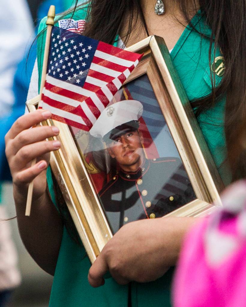 A Girl Scout holds a flag and a photographer of a deceased Marine veteran during the Veterans Day Parade on Thursday, Nov. 11, 2021 in Arlington, Wa. (Olivia Vanni / The Herald)