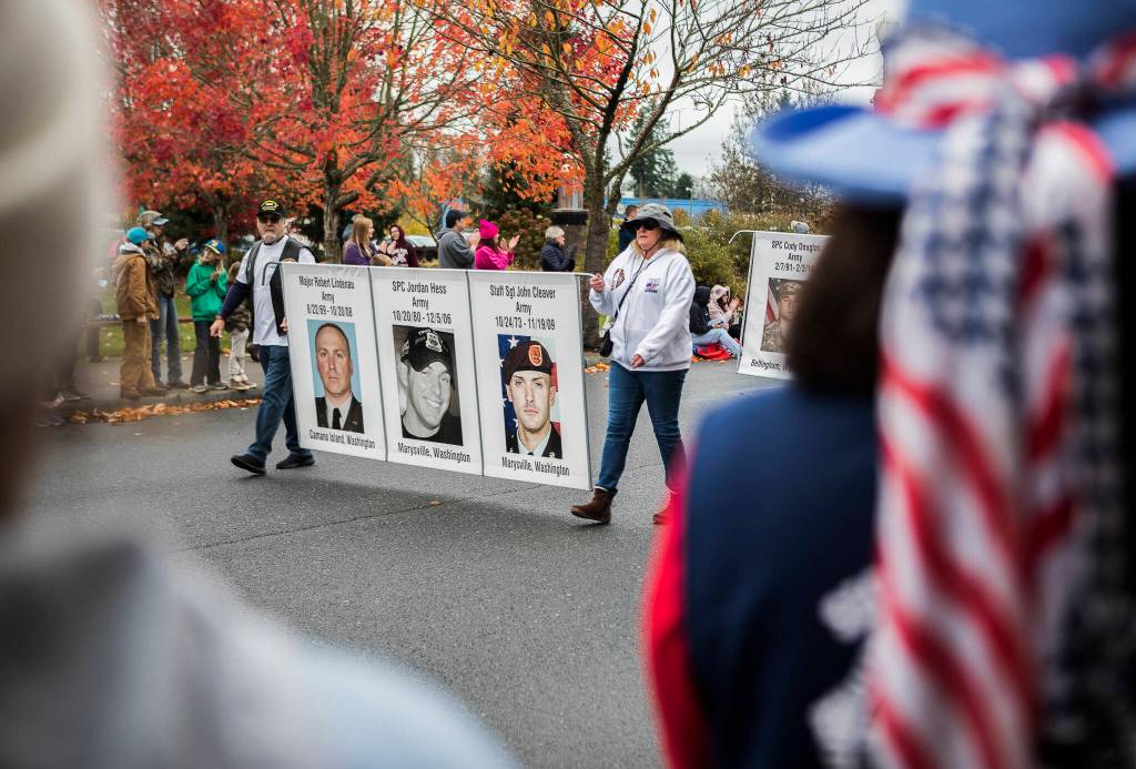 Photographs of deceased veterans are carried down Olympic Avenue during the Veterans Day Parade on Thursday, Nov. 11, 2021 in Arlington, Wa. (Olivia Vanni / The Herald)