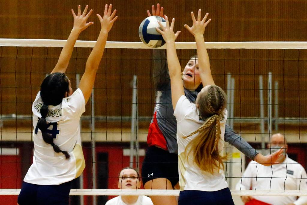 Arlingtons Chloe Fochesato, left, and Taylor Pederson jump to block a kill attempt by Stanwoods Olivia Rueckert Thursday evening during the 3A District volleyball playoffs at Marysville Pilchuck High School on November 11, 2021. (Kevin Clark / The Herald)