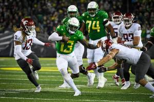 Oregon quarterback Anthony Brown (13) tries to avoid the tackle of Washington State defensive end Ron Stone Jr. (10) and linebacker Jahad Woods (13) during the third quarter of an NCAA college football game Saturday, Nov. 13, 2021, in Eugene, Ore. (AP Photo/Andy Nelson)