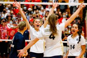 Arlington's Chloe Lewis, left to right, Emily Mekelburg, Malia Shepherd and Chloe Fochesato celebrate a point against Stanwood Thursday evening during the 3A District volleyball playoffs at Marysville-Pilchuck High School on November 11, 2021.            
(Kevin Clark / The Herald)