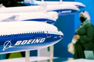 A woman walks by models of Boeing Co. aircraft, including the manufacturer's new Boeing 777X, at the Dubai Air Show in Dubai, United Arab Emirates, Wednesday, Nov. 17, 2021. (AP Photo/Jon Gambrell)