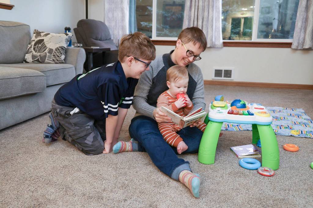 Kate Torrey plays with her sons, 9-month-old Oliver and older son Isaac, in their living room in Clearview. (Andy Bronson / The Herald)