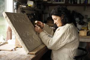 Alexandra Morosco works on a relief carving in her studio. The art piece is a thank-you gift to the kennel where she found her faithful canine companion, a Tibetan mastiff. (Kira Erickson / South Whidbey Record)
