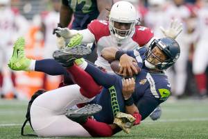 Seattle Seahawks quarterback Russell Wilson (3) is sacked by Arizona Cardinals' Chandler Jones, bottom, as Cardinals' Markus Golden (44) moves in on top during the second half of an NFL football game, Sunday, Nov. 21, 2021, in Seattle. (AP Photo/Ted S. Warren)