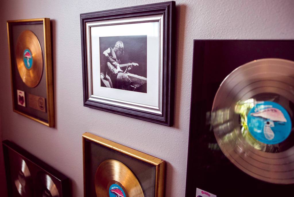 A photograph of Roger Fisher onstage in the 1970s is surrounded by platinum and gold Heart albums on a wall in his home. (Olivia Vanni / The Herald)