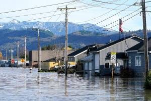 FILE - Floodwater inundates homes along a road on Nov. 17, 2021, in Sumas, Wash. Damages from flooding last week in northwest Washington's Whatcom County could reach as high as $50 million, officials said, as forecasters warn that multiple "atmospheric rivers" may drench the Pacific Northwest in coming days. (AP Photo/Elaine Thompson, File)